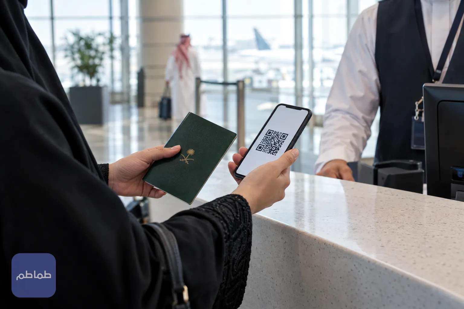 يد مسافر تحمل جواز سفره وهاتفه أمام نقطة خدمة في مطار إماراتي