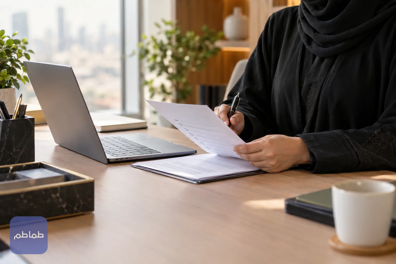 موظفة موارد بشرية تراجع قائمة مسميات وظيفية مطبوعة إلى جانب حاسوب في مكتب حديث