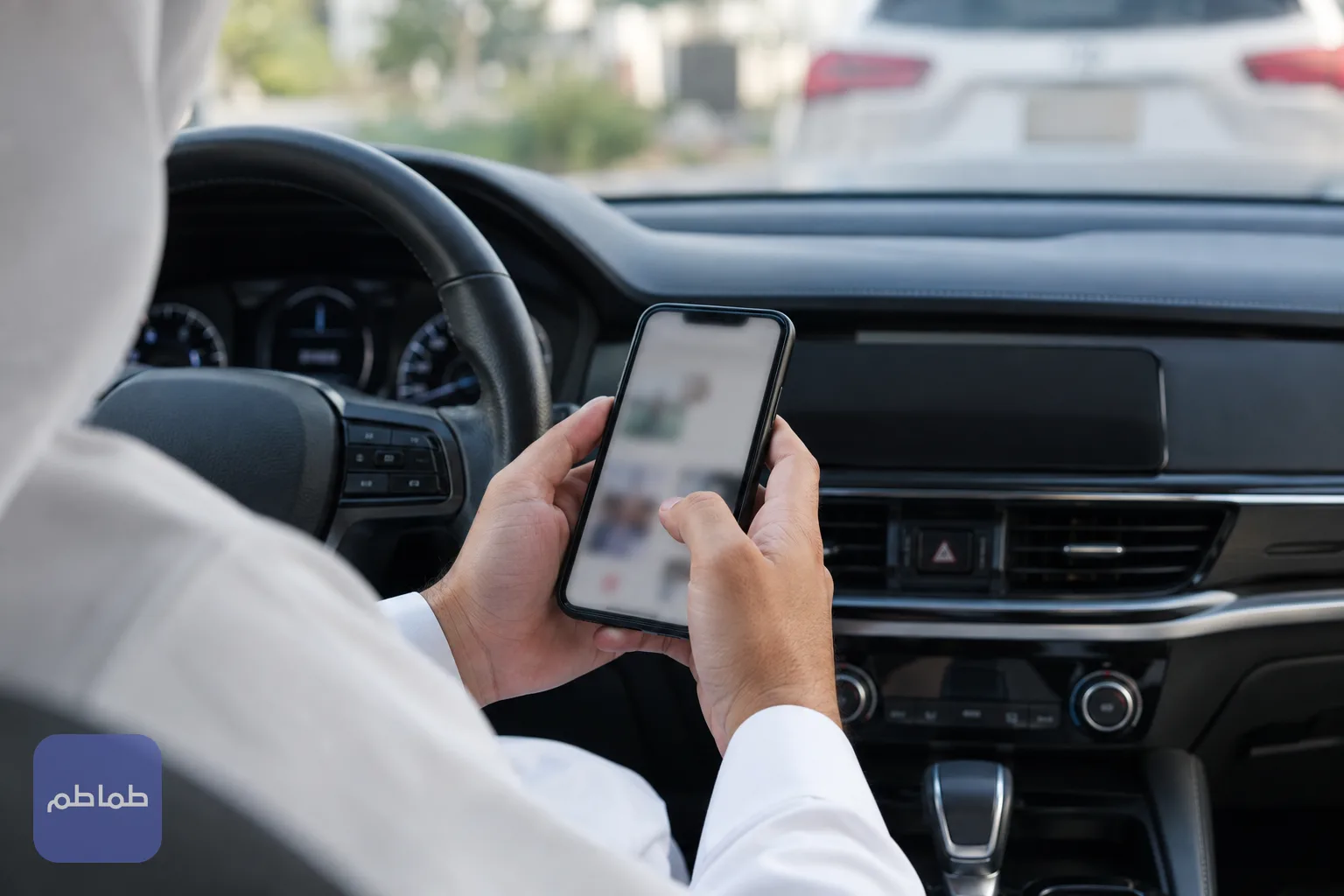 شخص يمسك هاتفًا داخل سيارة متوقفة أثناء متابعة خطوات التسجيل